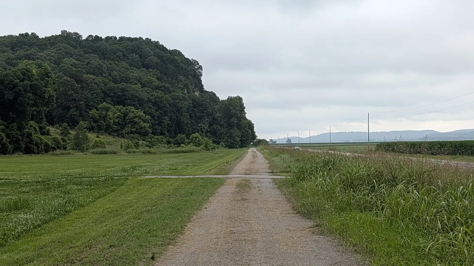 A rural Missouri trail extending between fields and wooded hills